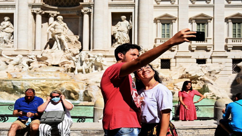 سائحان يلتقطان صورة ذاتية قرب نافورة تريفي في وسط العاصمة الإيطالية روما، 19 آب/أغسطس 2020. (فيتشنزو بينتو/ أ ف ب)