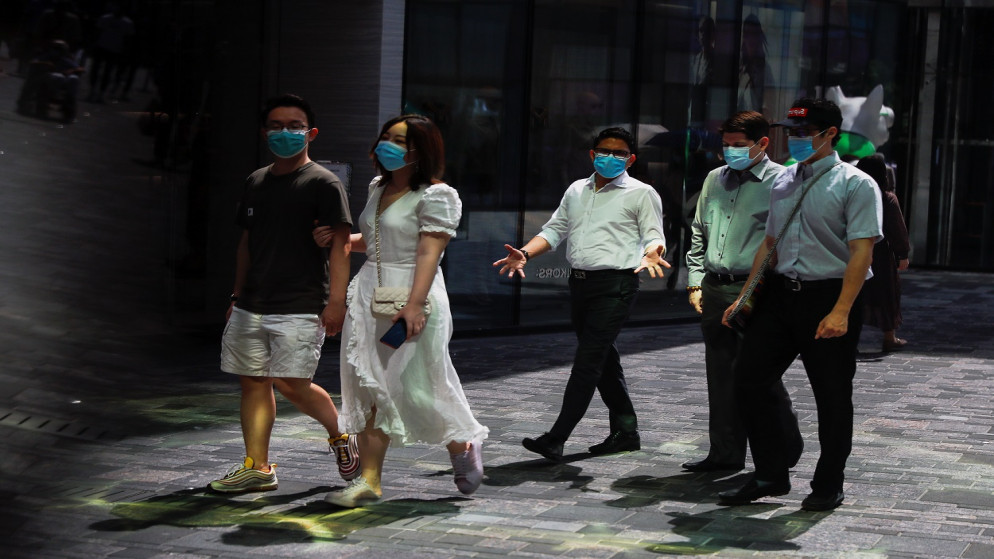 ينعكس الناس في نافذة متجر أثناء سيرهم في مجمع تسوق بعد تفشي مرض فيروس كورونا (COVID-19) في بكين، الصين، 25 أغسطس 2020. (رويترز)