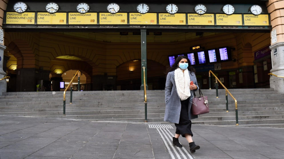 سيدة تخرج من محطة فليندرز في ملبورن الأسترالية في اليوم الأول من إلزام السكان بارتداء كمامات في الأماكن العامة لمنع انتشار فيروس كورونا. 23/07/2020. (وليام ويست / أ ف ب)