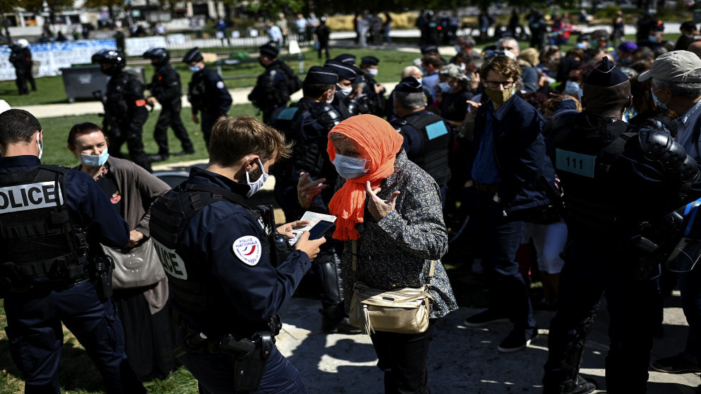 امرأة تتجادل مع شرطي خلال احتجاج على ارتداء أقنعة الوجه الإلزامي في باريس. 29 أغسطس 2020. (أ ف ب)