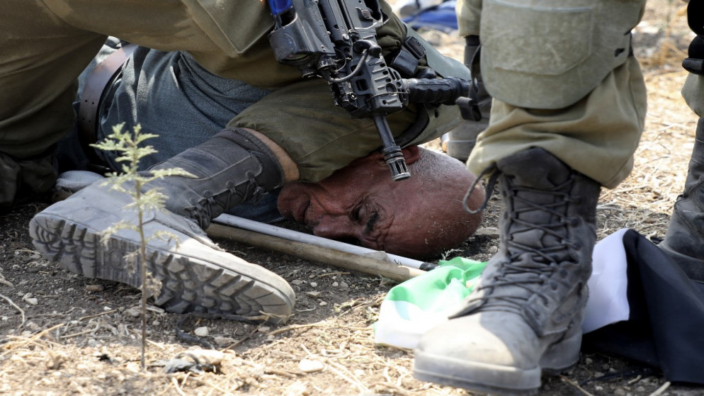 جندي احتلال إسرائيلي يجثو بركبته على رقبة الناشط الفلسطيني خيري حنون في منطقة "شوفة" شمالي الضفة الغربية المحتلة، 1 أيلول/سبتمبر 2020. (جعفر اشتية/ أ ف ب)