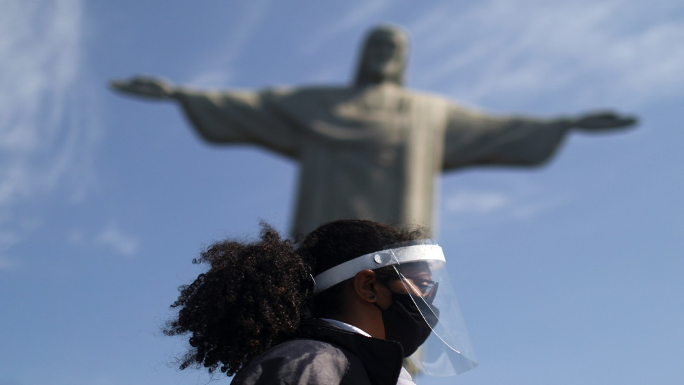 حارس يرتدي درعًا وقناعًا للوجه أثناء إعادة فتح تمثال المسيح بعد إغلاق دام شهورًا بسبب تفشي فيروس كورونا، في ريو دي جانيرو، البرازيل، 15 أغسطس 2020. (رويترز)
