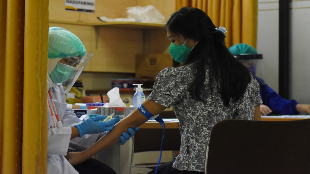 متطوعة (على اليمين) أخذت عينات دم قبل أن تتلقى لقاح فيروس كورونا COVID-19 تُ، 6 أغسطس 2020. (أ ف ب)