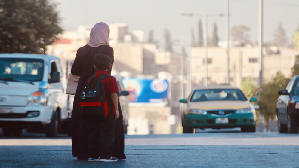 صورة أرشيفية لسيدة ترافق ابنها إلى مدرسته. (صلاح ملكاوي / المملكة)