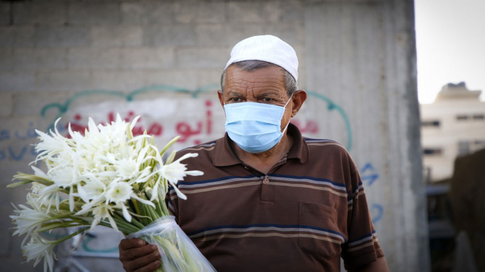 فلسطيني يرتدي كمامة واقية يبيع الزهور في قطاع غزة وسط حصار تفرضه جائحة فيروس كورونا. 03/09/2020. (محمد عابد / أ ف ب)