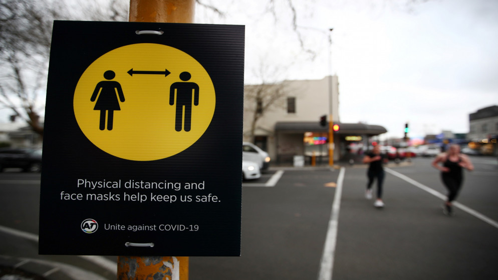 أشخاص يركضون أمام شاخصة لإلزام التباعد الاجتماعي ضمن إجراءات السلامة العامة من فيروس كورونا المستجد في نيوزيلندا. 31/08/2020. (فيونا جودال/ رويترز)