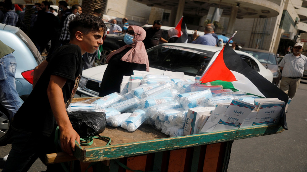 شاب فلسطيني  يبيع أقنعة واقية للوجه خلال احتجاج على تطبيع العلاقات مع اسرائيل في نابلس بالضفة الغربية المحتلة . 15 سبتمبر ، 2020. (رويترز / رنين صوافطة)