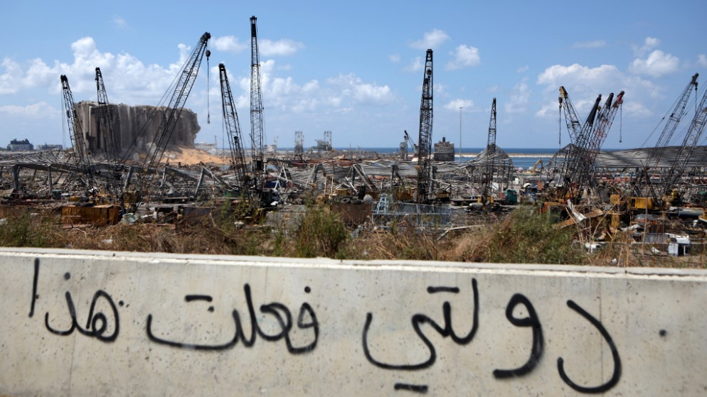 عبارة على جدار تُحمل الدولة اللبنانية مسؤولية انفجار بيروت وفي الخلفية يبدو الدمار الذي لحق بالمرفأ، 8 أيلول/سبتمبر 2020. (أ ف ب)