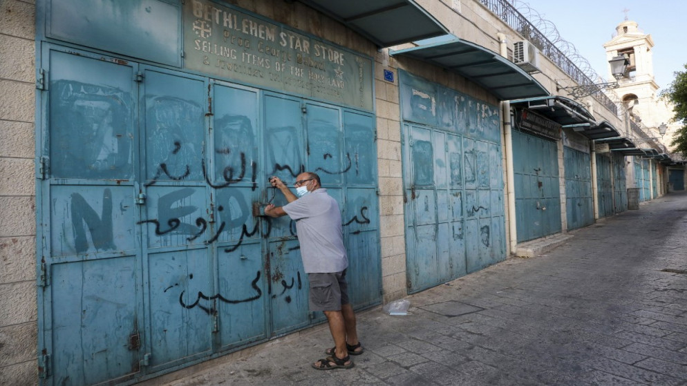 فلسطيني يغلق متجره في شارع رئيسي في مدينة بيت لحم، وسط إغلاق بسبب جائحة كوفيد -19 في الضفة الغربية المحتلة. 26/09/2020. (حازم بادر / أ ف ب)