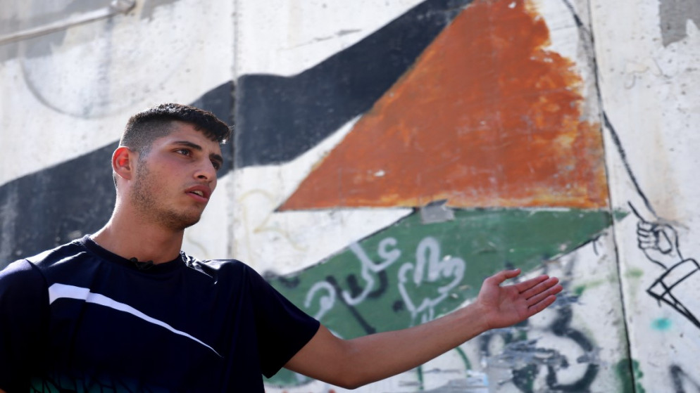 مؤيد عفانة، طالب فلسطيني، يشير إلى جدار يفصل القدس الشرقية عن قرية أبو ديس الفلسطينية في الضفة الغربية المحتلة. 23/09/2020. (إيمانويل دوناند / أ ف ب)
