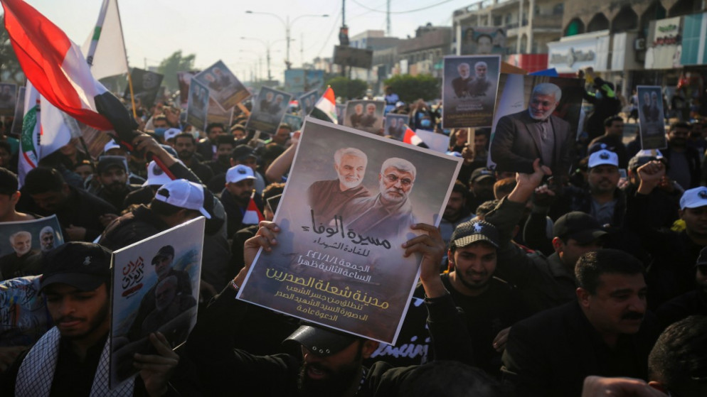 أنصار لقوات الحشد الشعبي يحملون صوراً لأبو مهدي المهندس والجنرال الإيراني قاسم سليماني خلال مظاهرة في حي الشعلة الغربي في بغداد، 1 كانون الثاني/يناير 2021. (أ ف ب)