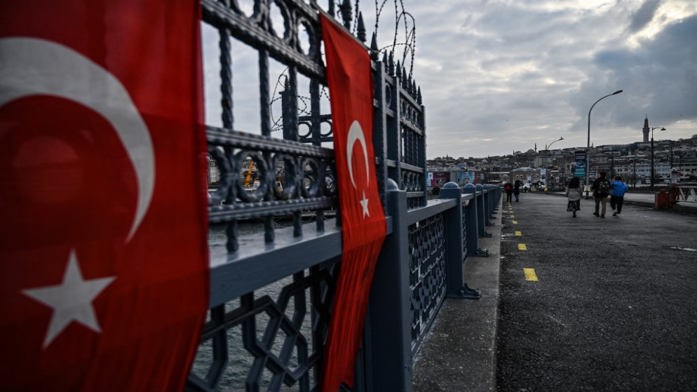 أشخاص يسيرون على جسر جالاتا المهجور، بالقرب من منطقة كاراكوي، في إسطنبول خلال حظر تجول في نهاية الأسبوع، بهدف الحد من انتشار كوفيد -19 الناجم عن فيروس كورونا، 19 كانون الأول/ ديسمبر 2020. (أ ف ب)