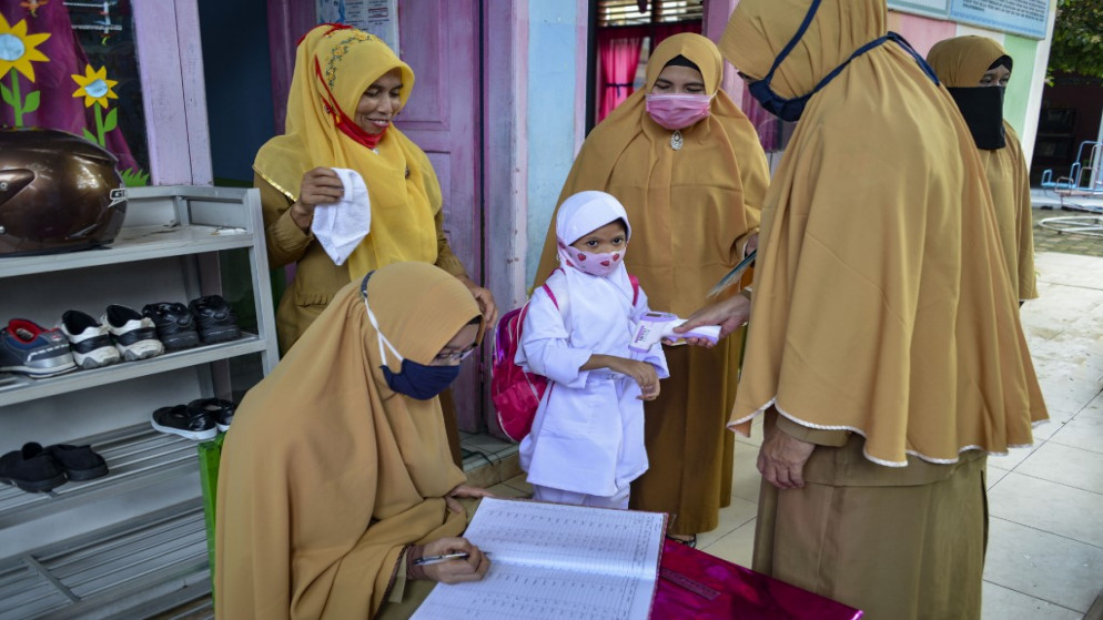 معلمون يقومون بفحص درجة حرارة جسم التلاميذ كإجراء وقائي ضد فيروس كورونا Covid-19 في روضة أطفال في باندا آتشيه في 5 يناير 2021. اندونسيا. (أ ف ب)