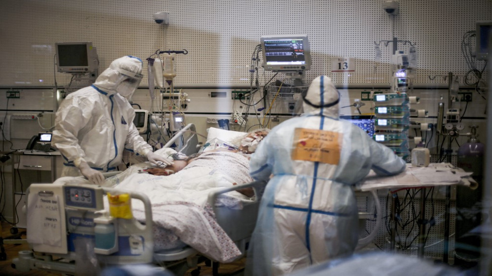 عاملون طبيون يعتنون بمريض في جناح عزل فيروس كورونا COVID-19، في المركز الطبي زيف في مدينة صفد شمال إسرائيل، 24 كانون الأول/ ديسمبر 2020. (أ ف ب)