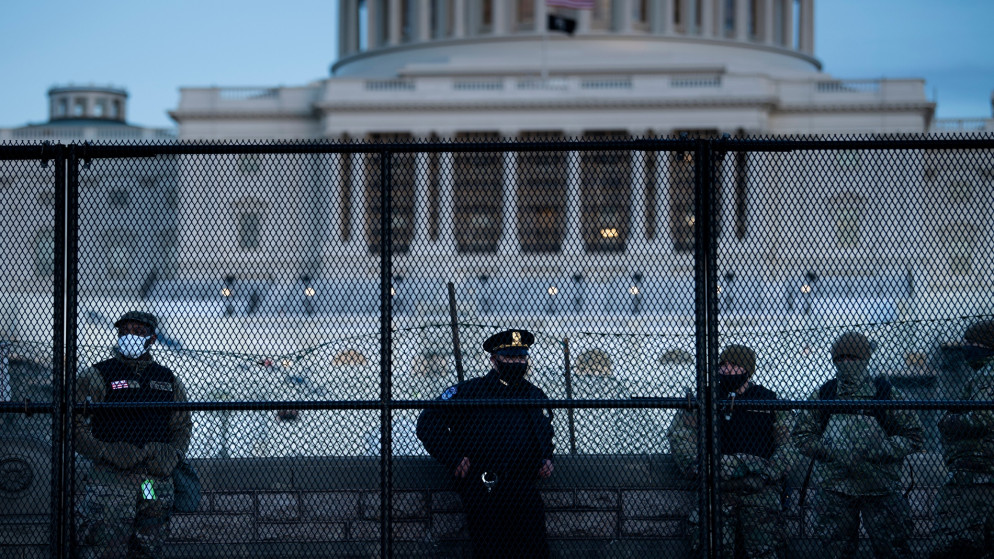 ضابط شرطة يقف في "الكابيتول" مع أعضاء من الحرس الوطني للسيطرة على الحشود يحيط بمبنى الكابيتول الأميركي. 7 يناير 2021. واشنطن