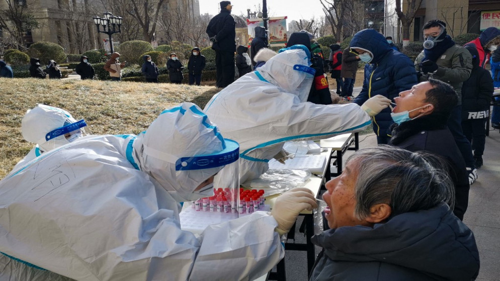 عاملون طبيون يأخذون عينات مسحة من السكان خارج مجمع سكني بعد تفشي الفيروس، في شيجياتشوانغ، مقاطعة خبي شمال الصين، 6 كانون الثاني/ يناير 2021. (أ ف ب)