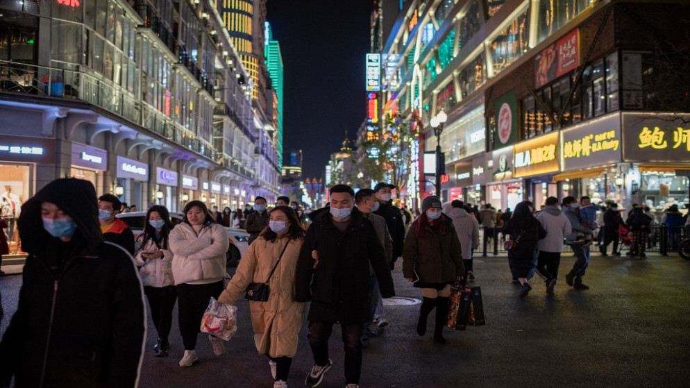 أشخاص يرتدون كمامات للوجه، يمشون في شارع جيانغان في ووهان، عشية الذكرى السنوية الأولى لتأكيد الصين أول وفاة بفيروس كورونا، 10 كانون الثاني/ يناير 2021. (أ ف ب)