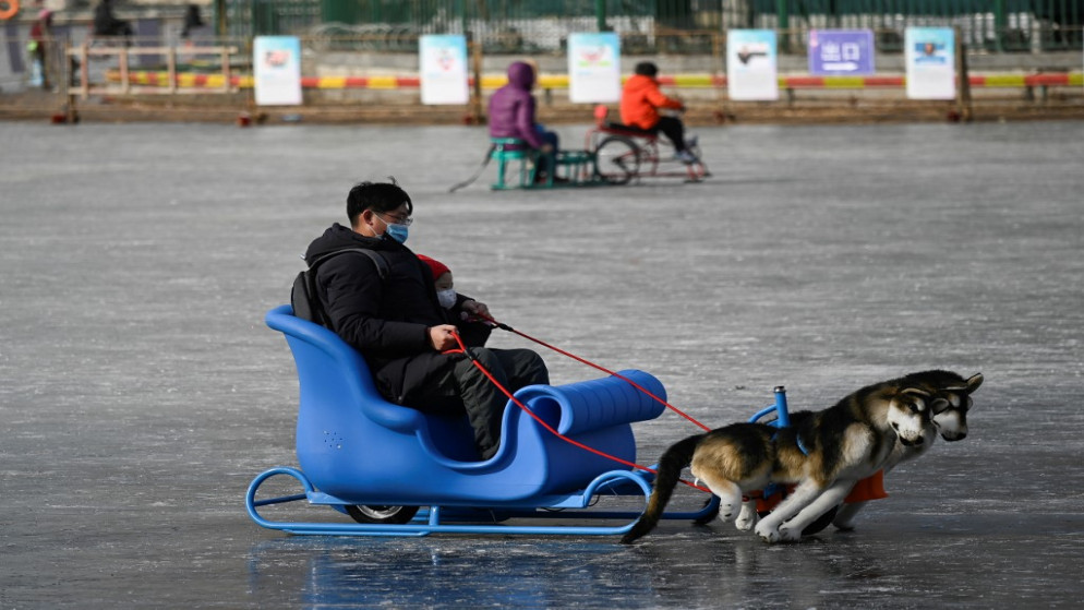 رجل وطفل يستخدمان زلاجة في بحيرة متجمدة في بكين في 12 يناير 2021. (وانغ تشاو / أ ف ب)