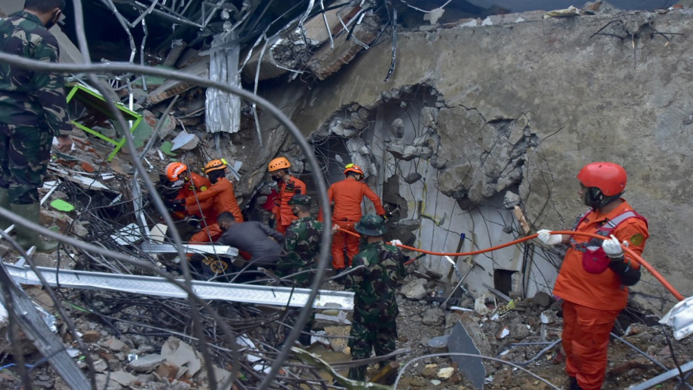 رجال الإنقاذ يبحثون عن ناجين في مبنى منهار في ماموجو، 15 كانون الثاني/يناير 2021. (أ ف ب)