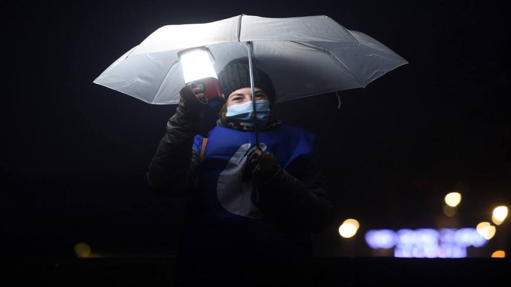 امرأة ترتدي كمامة تشارك في تجمع لحوالي 2000 شخص يحملون أضواء ومظلات بيضاء لدعم سجناء الباسك وللدعوة إلى تحسين ظروف الاحتجاز على ضفاف نهر نايف في بايون، 9 كانون الثاني/يناير 2021. (أ ف ب)