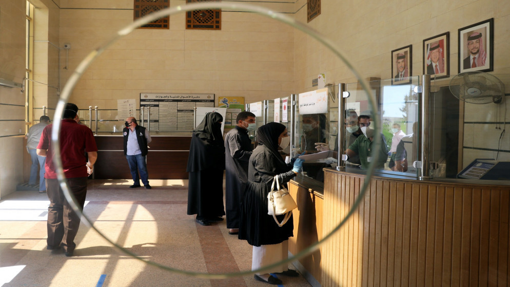 أشخاص يرتدون كمامات واقية في دائرة الأحوال المدنية بعد عودة موظفي القطاع العام في الأردن. 26/05/2020. (محمد حامد/ رويترز)