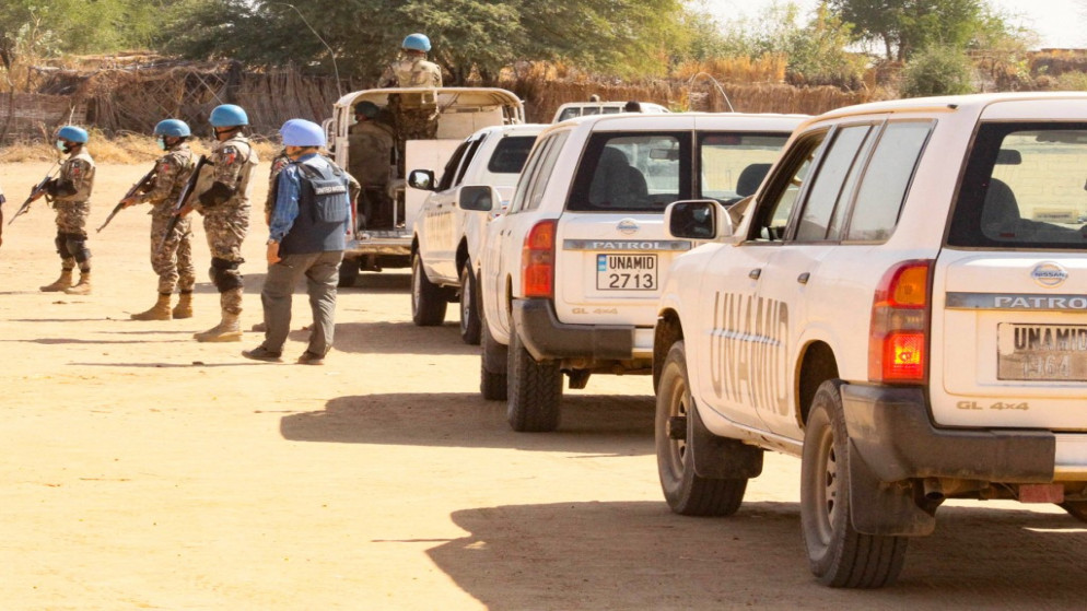 أعضاء من بعثة حفظ السلام التابعة للأمم المتحدة والاتحاد الأفريقي (يوناميد) يجتمعون مع سياراتهم في مخيم كلمة للنازحين داخليًا في نيالا، عاصمة جنوب دارفور، 31 كانون الأول/ ديسمبر 2020. (أ ف ب)