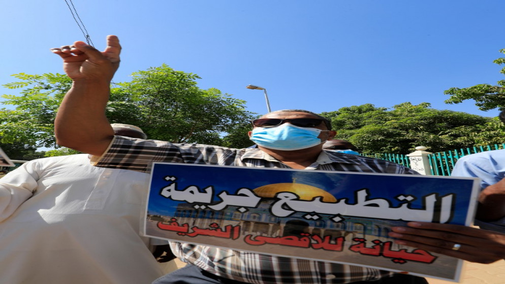 متظاهر سوداني يحمل لافتة عليها صورة قبة الصخرة ورسالة باللغة العربية تقول "التطبيع جريمة، خيانة للأقصى المبارك" خلال مسيرة في الخرطوم رافضة للتطبيع مع إسرائيل. 17/01/2021. (أ ف ب)