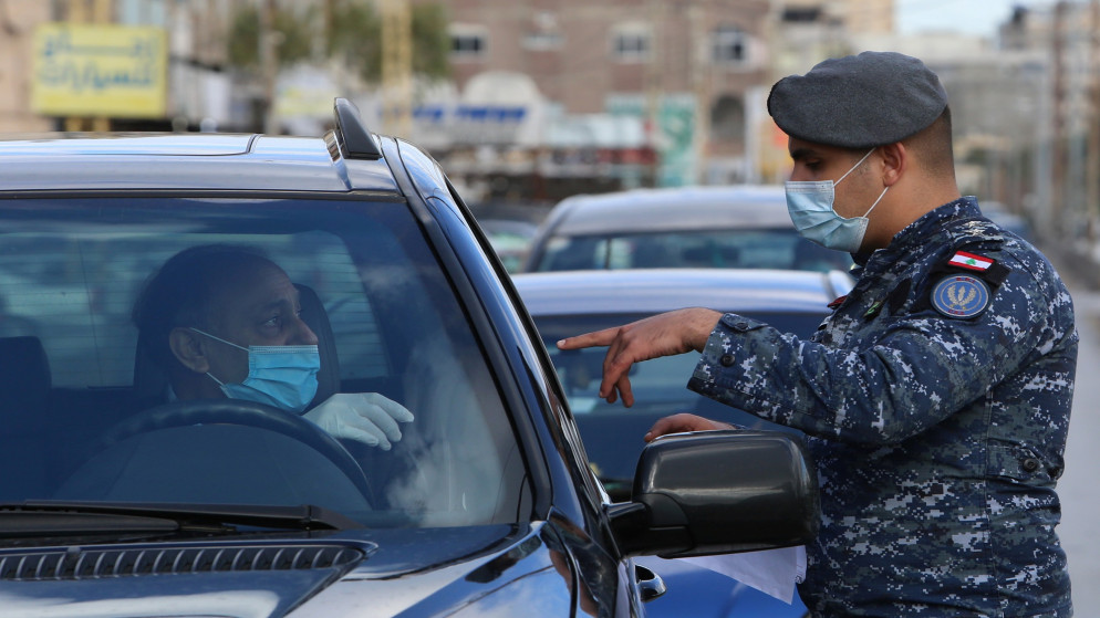 رجل أمن يرتدي كمامة للوجه يتحدث مع سائق عند نقطة تفتيش في صيدا في لبنان؛ للحد من انتشار فيروس كورونا المستجد. 15/01/2021. (عزيز طاهر/ رويترز)
