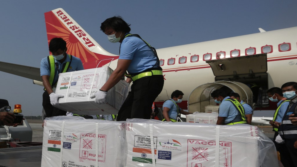 عمال يقومون بتفريغ علب كرتون لقاح لفيروس كورونا Covid-19 يتم تسليمه من الهند إلى ميانمار ، في مطار يانغون الدولي في يانغون .22 يناير 2021.(أ ف ب)