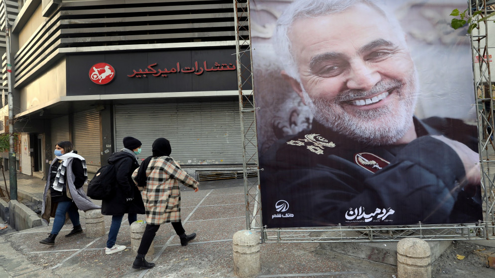 أشخاص يسيرون بالقرب من صورة القائد العسكري الإيراني قاسم سليماني في ذكرى مرور عام على مقتله في هجوم أميركي في طهران، إيران، 1  كانون الثاني/يناير 2021 (رويترز)