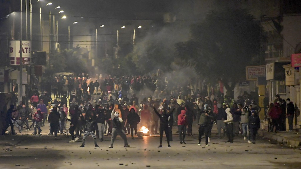 متظاهرون يقفون وسط الأدخنة، خلال اشتباكات مع قوات الأمن في ضاحية مدينة التضامن، العاصمة تونس، 18 كانون الثاني/ يناير 2021. (أ ف ب)