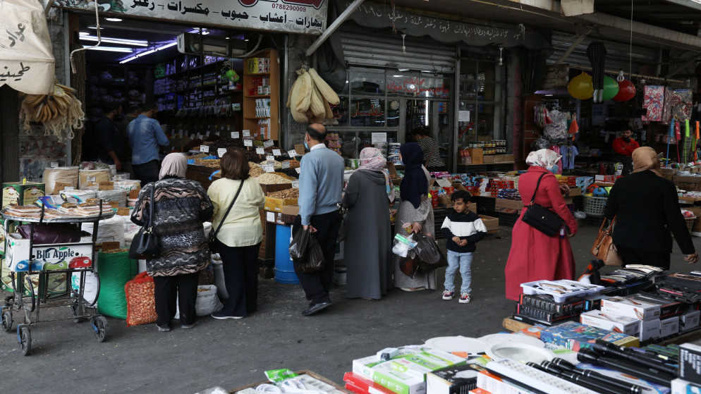 مواطنون يتسوقون أمام سوق تجاري في عمّان في ظل إجراءات احترازية للوقاية من فيروس كورونا المستجد. (رويترز)