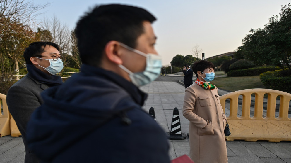 أشخاص يرتدون أقنعة الوجه بجوار منطقة الوصول في فندق هيلتون ووهان أوبتيكس فالي حيث يقيم أعضاء فريق منظمة الصحة العالمية. 28 يناير 2021. (أ ف ب)