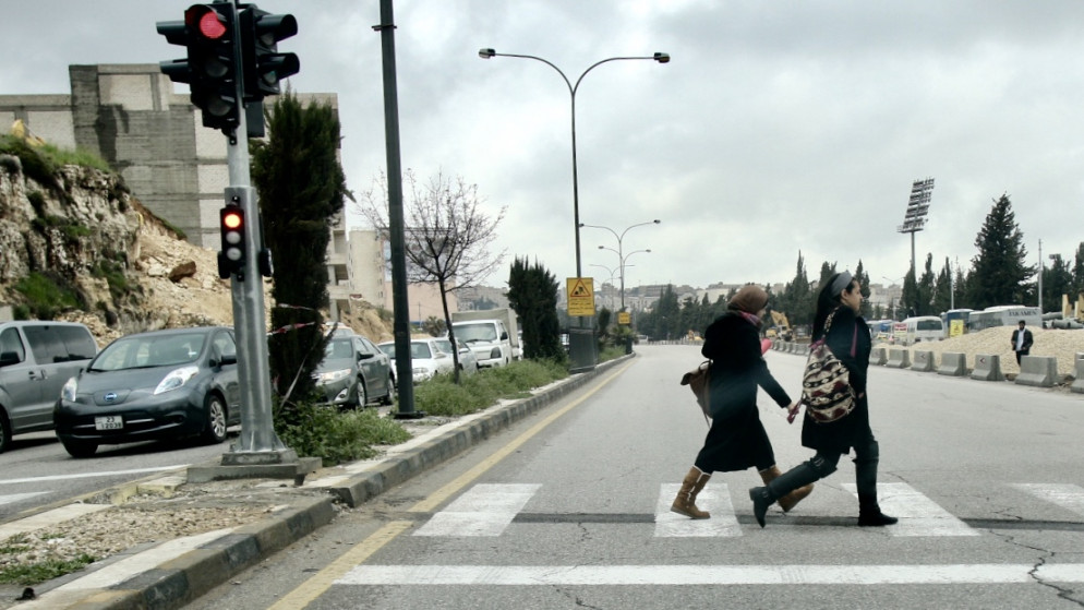 سيدتان تسيران في شارع رئيسي في عمّان وتظهر السماء فوقهما غائمة. (صلاح ملكاوي/ المملكة)