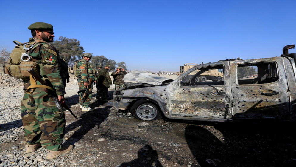 جنود من الجيش الوطني الأفغاني يتفقدون حطام سيارة عسكرية محترقة في موقع انفجار في جلال آباد. (رويترز)