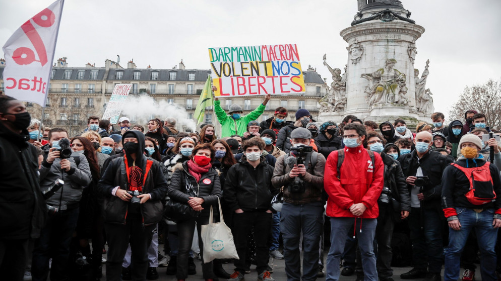 شخص يحمل لافتة كتب عليها "دارمانين ماكرون يسرق حرياتنا" أثناء مظاهرة ضد مشروع قانون "الأمن الشامل"، في باريس، فرنسا، 30 كانون الثاني/يناير 2021. (رويترز / بينوا تيسييه)