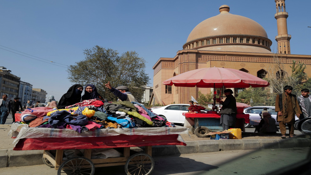 بائع ملابس يتحدث لامرأة في كابل في أفغانستان. (رويترز)