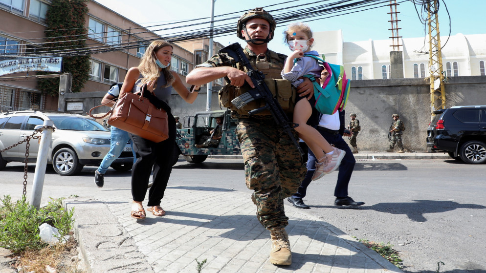 جندي من الجيش يحمل طفلا في الوقت الذي يفر فيه مدنيون بعد إطلاق نار بالقرب من احتجاج في بيروت، 14 أكتوبر/تشرين الأول 2021. (رويترز)
