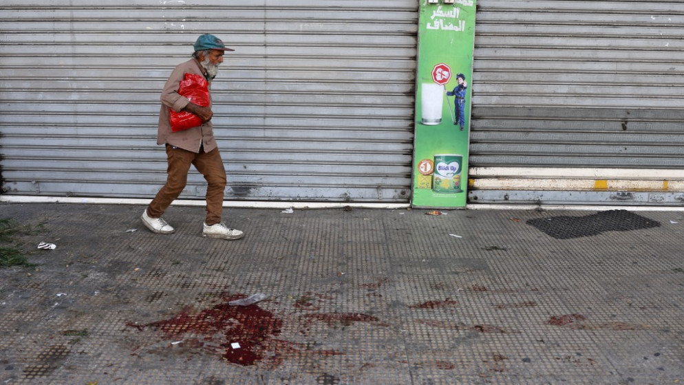رجل يسير بالقرب من دماء على الأرض في منطقة الطيونة في الضاحية الجنوبية للعاصمة اللبنانية بيروت، 14 تشرين الأول/أكتوبر 2021. (أ ف ب)