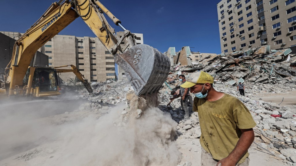 عمال فلسطينيون يجمعون أنقاض مبنى دمره الاحتلال الإسرائيلي في غارة جوية خلال الاعتداء الأخير على قطاع غزة، 22 حزيران/ يونيو 2021. (أ ف ب)