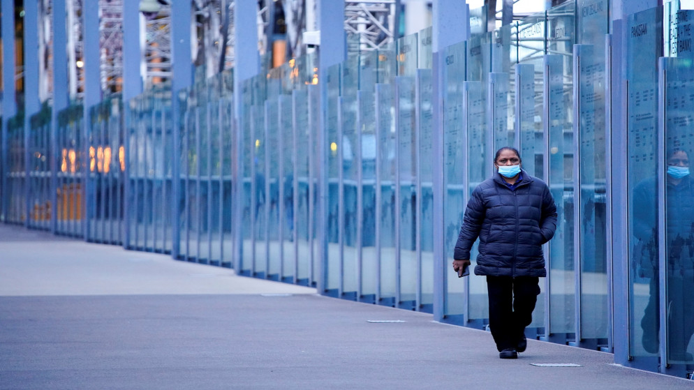 امرأة ترتدي كمامة وتسير على جسر مدينة مهجور خلال ساعات التنقل الصباحية في اليوم الأول من الإغلاق للحد من انتشار مرض فيروس كورونا في ملبورن. أستراليا، 16 تموز/يوليو 2021. (رويترز/ ساندرا ساندرز)