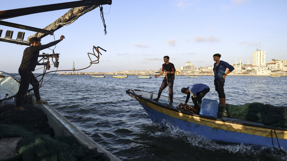 صياد فلسطيني يلقي حبلا لتشكيل قافلة مع قارب آخر قبالة ساحل مدينة غزة. 22/09/2021. (محمود حمس/ أ ف ب)