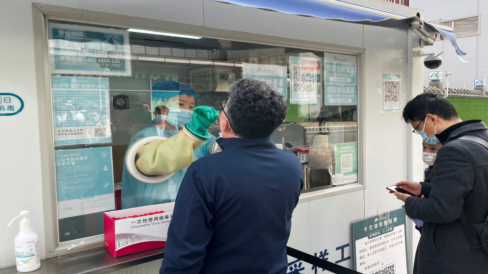 عامل طبي خلف زجاج يجمع مسحة من رجل لإجراء اختبار فحص كورونا خارج مركز تجاري في بكين بعد ارتفاع إصابات كورونا في الصين. 25/10/2021. (كارلوس جارسيا رولينز/ رويترز)