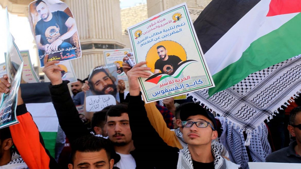 متظاهرون يحملون صور أسرى فلسطينيين مضربين عن الطعام خلال وقفة تضامنية في مدينة الخليل،  24/10/2021، (وفا/سمر بدر)