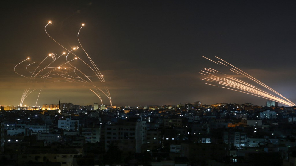 نظام القبة الحديدية الإسرائيلي (يسار) يحاول اعتراض صواريخ المقاومة الفلسطينية (يمين) في سماء قطاع غزة، 14 أيار/ مايو 2021. (أنس البابا/ أ ف ب)