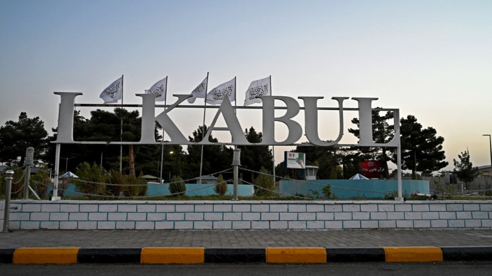 تظهر أعلام طالبان خلف لافتة مثبتة خارج مطار كابل، 9 سبتمبر/أيلول 2021. (أ ف ب)