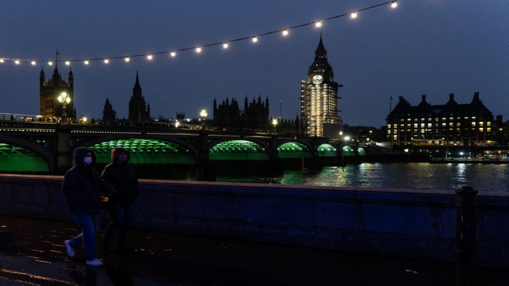 مشاة يسيرون على طول جسر نهر التايمز وظهور البرلمان في الخلفية في وسط لندن .11 ديسمبر 2021.(أ ف ب)