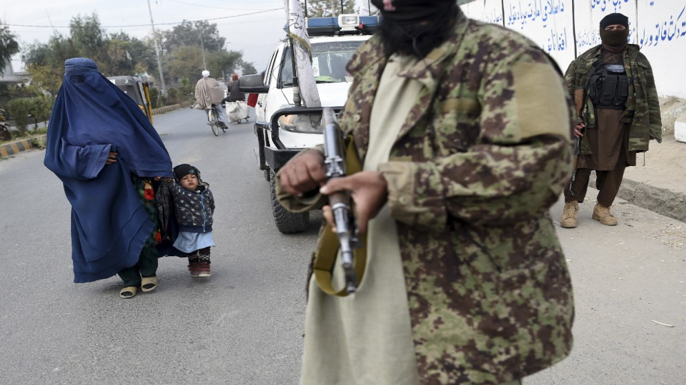 عناصر من حركة طالبان في أفغانستان وتسير بجانبهم امرأة وطفلها. (أ ف ب)