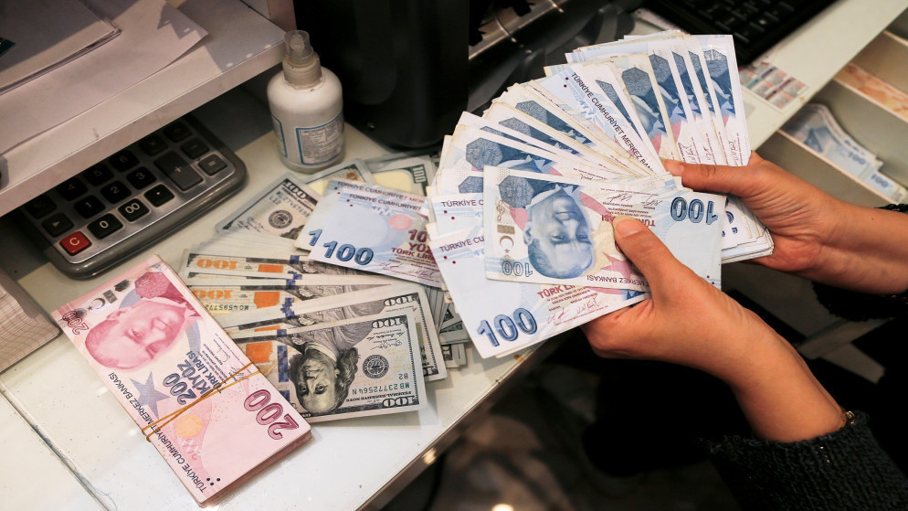 شاب يعمل في مكتب صرافة في أنقرة يحمل نقودا بالليرة التركية. (رويترز)