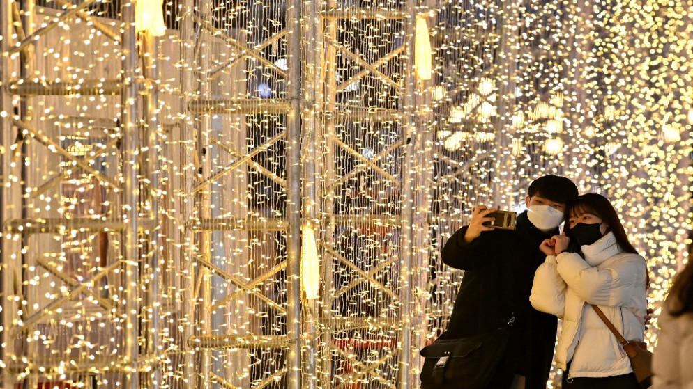 أشخاص يلتقطون صورًا أثناء زيارتهم لعرض أضواء عيد الميلاد وسط سول، 23 ديسمبر 2021. (أ ف ب)